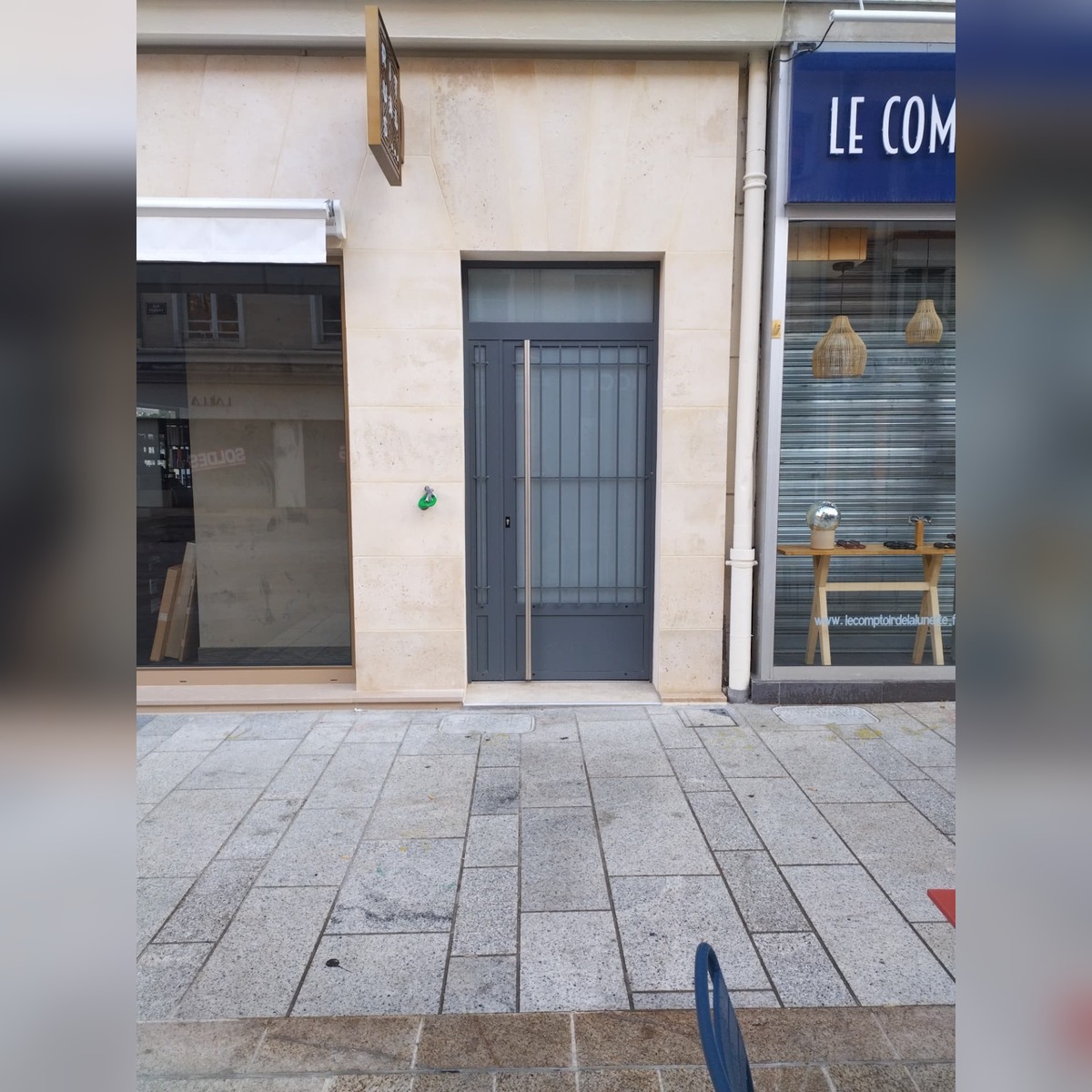 Porte d'entrée en aluminium gris anthracite posée dans un encadrement en pierre de taille