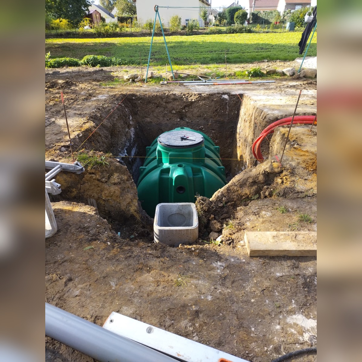 Cuve d'assainissement individuel posée en fouille avec regard béton et gaines techniques